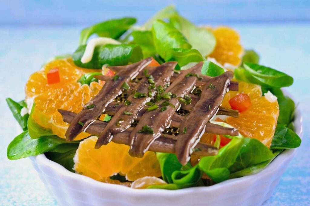 Fresh Andalusian orange salad with anchovies served over crisp greens, showcasing bright citrus segments and Mediterranean flavors.