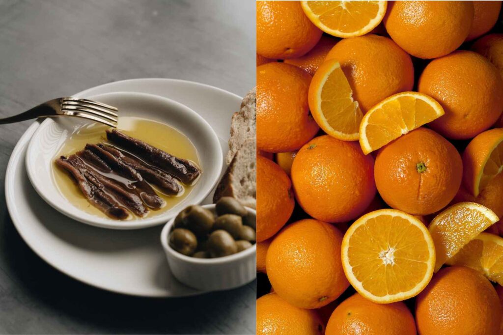 Simple Spanish orange salad with anchovies arranged on a white plate, served with olives and rustic bread.