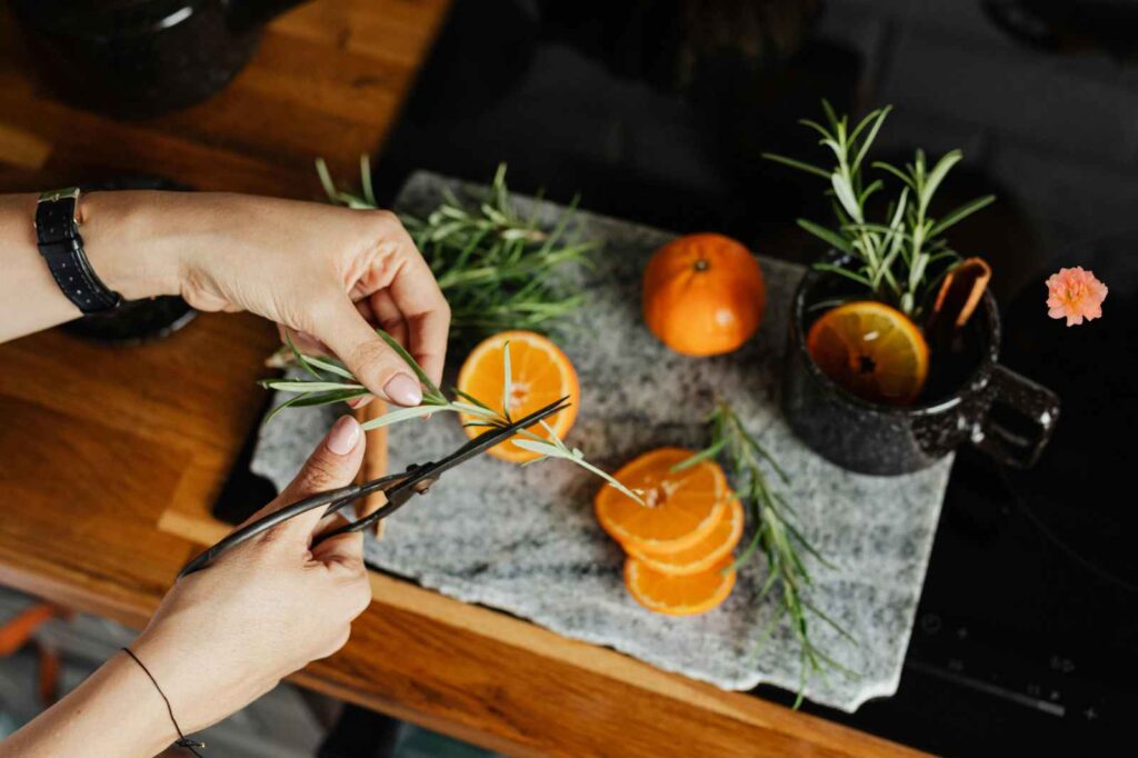 Hands slicing fresh oranges on a wooden board, preparing ingredients for an Andalusian orange salad with anchovies.