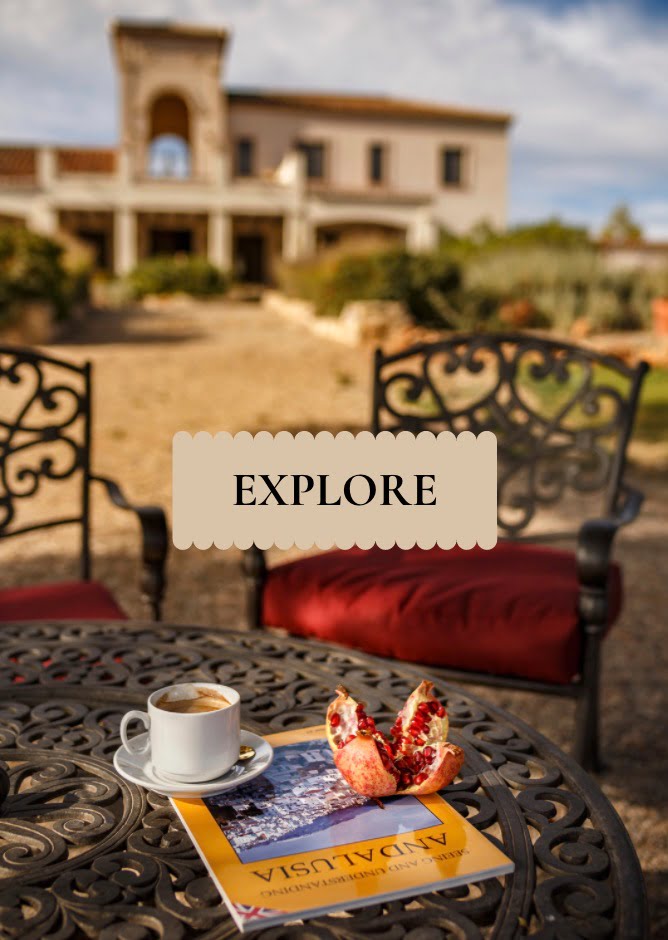EXPLORE-1 Morning coffee and pomegranate on a wrought-iron terrace table at La Esperanza Granada private villa in Spain, overlooking the hacienda’s Spanish Mission–style façade — an invitation to explore Andalusia’s countryside charm and heritage.