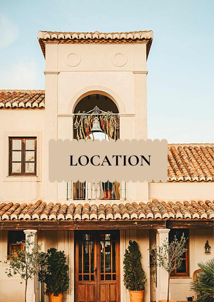 Spanish_Mission_Style_Hacienda_in_Spain Front façade of La Esperanza Granada private villa in Andalusia, with its arched bell tower, terracotta roof tiles, and rustic wooden doors framed by olive trees — a signature Andalusian hacienda landmark in the hills near Granada, Spain.