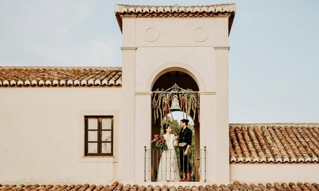 Bride and groom on the balcony of La Esperanza Granada private villa in Spain, celebrating their wedding with panoramic mountain views and classic Andalusian architecture.